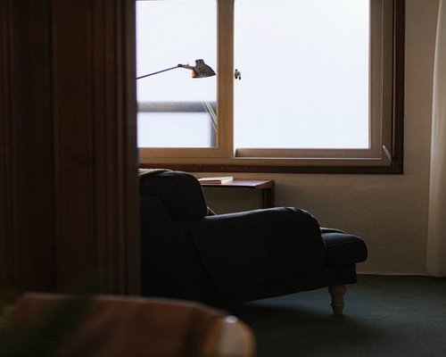 A well-lit cozy reading corner with a soft armchair and a warm standing lamp beside a window