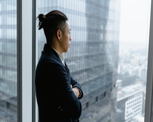 Person looking out of a high-rise office window at the distant city skyline